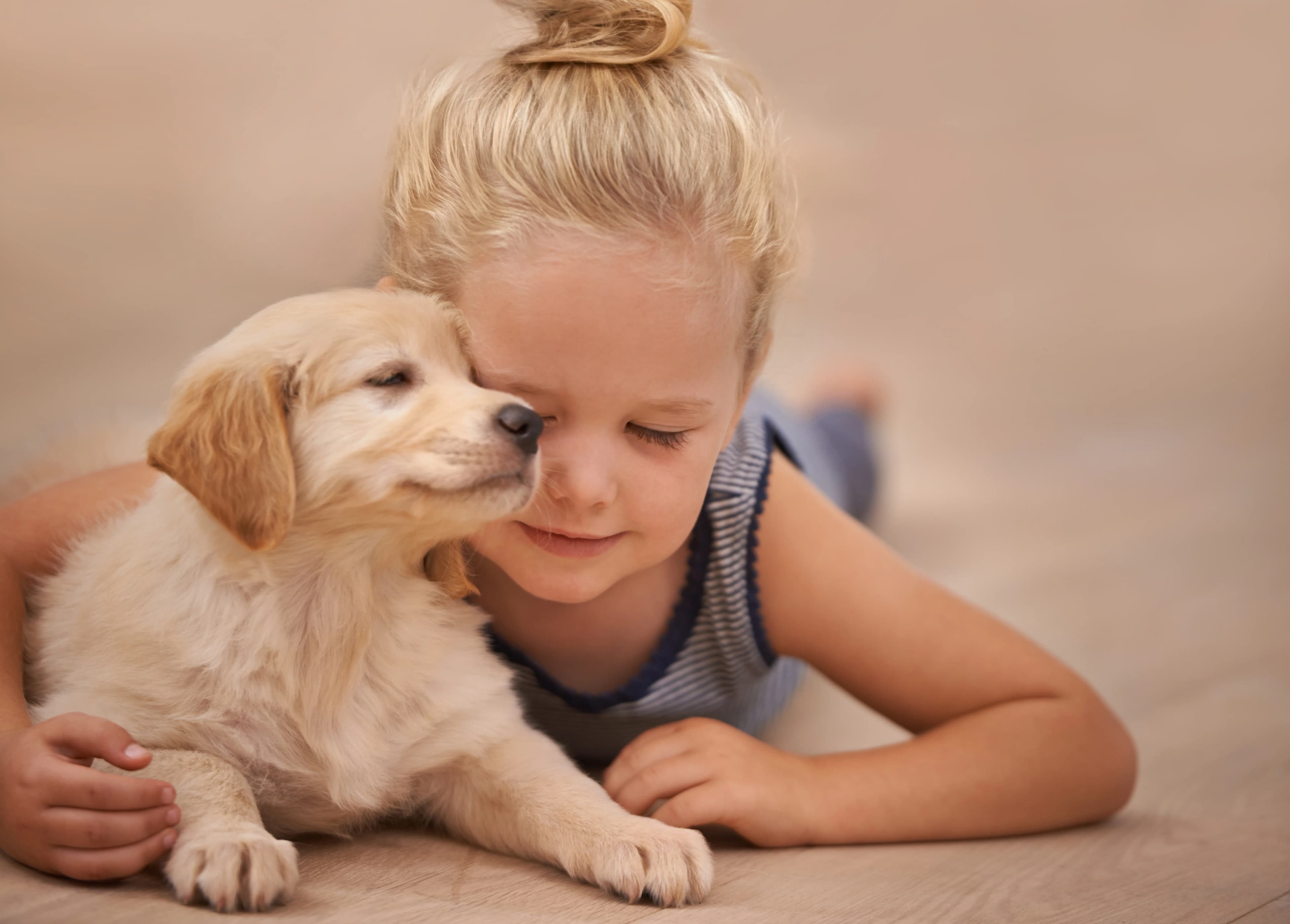A young girl resting cheek-to-cheek with her sleepy golden retriever puppy