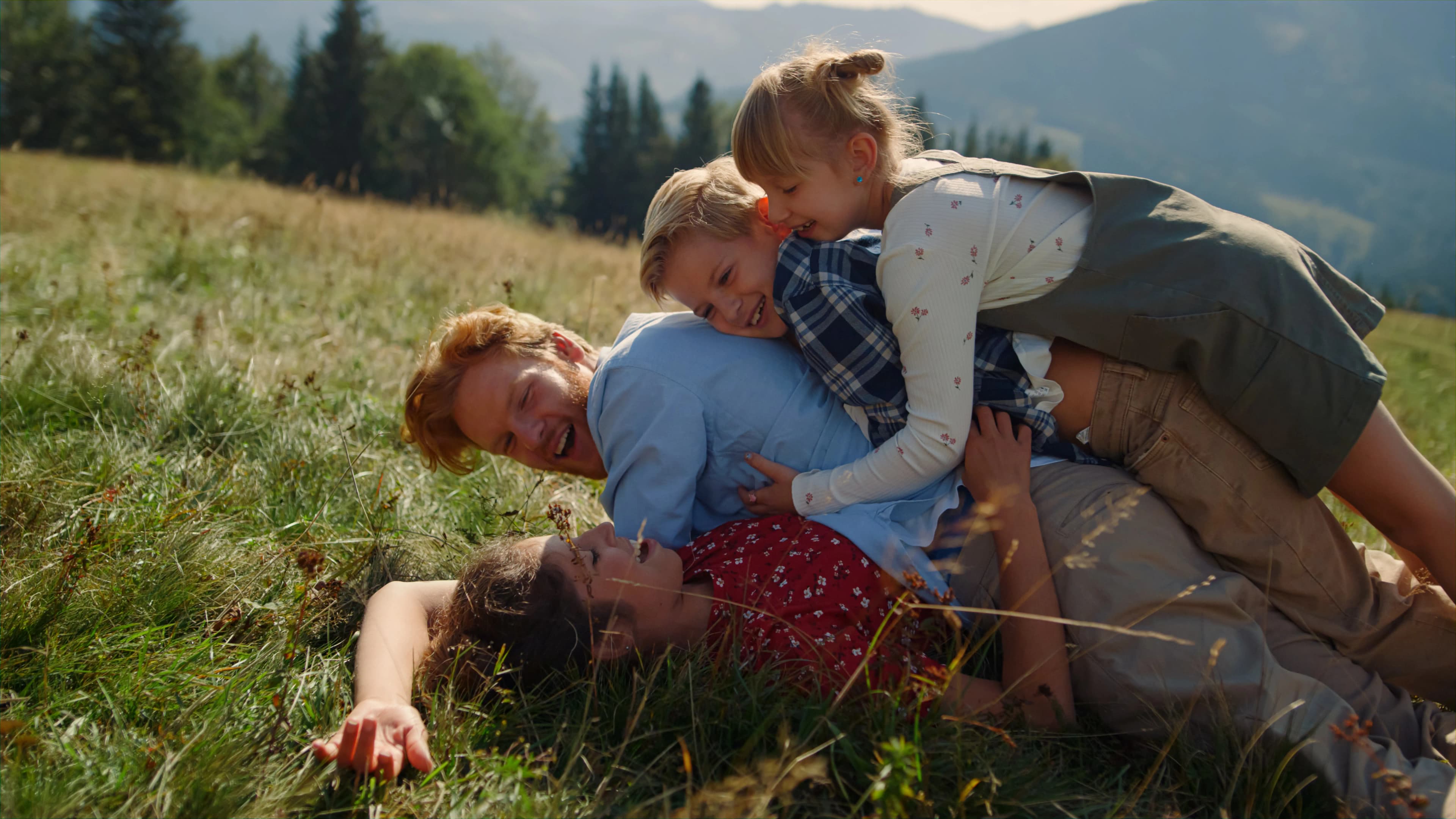 A family relaxing together with their dog on a grassy hillside