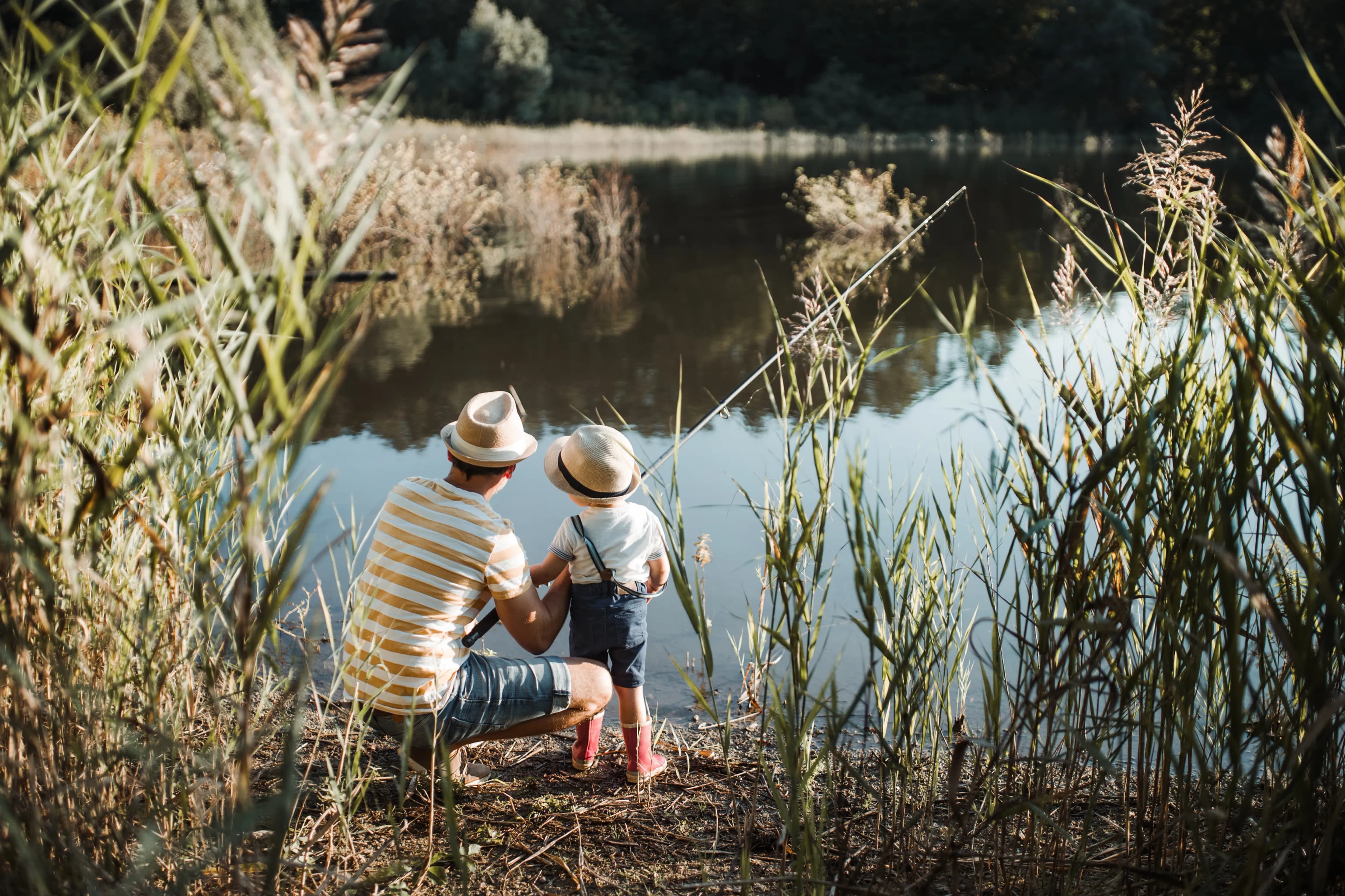 A father and child sharing a quiet moment beside the lake with their dog