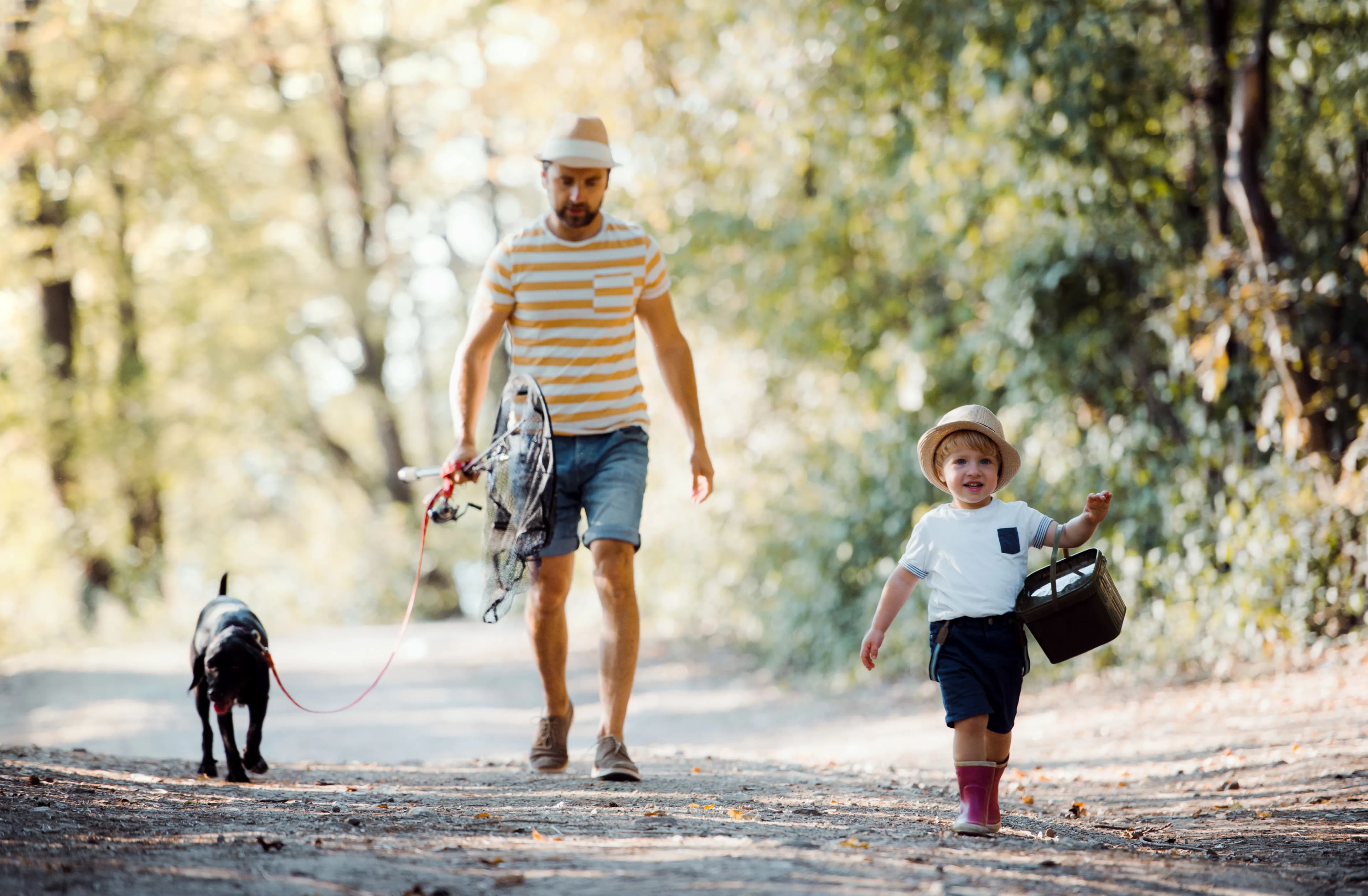 A father, child, and dog walking home together through nature